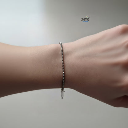Silver bracelet on a wrist with a plain background