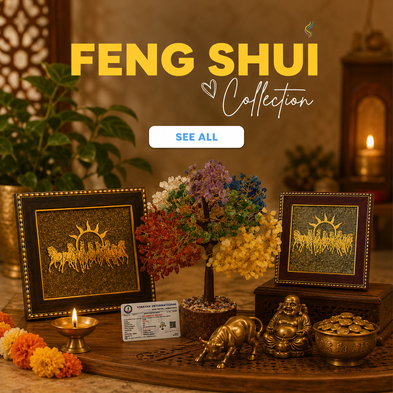 A styled indoor display for a Feng Shui collection, featuring two framed gold-toned artwork pieces, a small multicolored tree of life, brass figurines, candles, flowers, and decorative objects arranged on a wooden surface. Large text at the top reads 'FENG SHUI Collection' with a 'SEE ALL' button below.